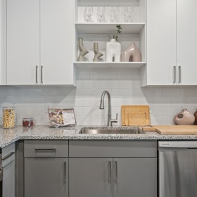 ontemporary kitchen at Momentum Blanding Apartments with stainless steel appliances, open shelving, and sleek white and gray cabinetry.