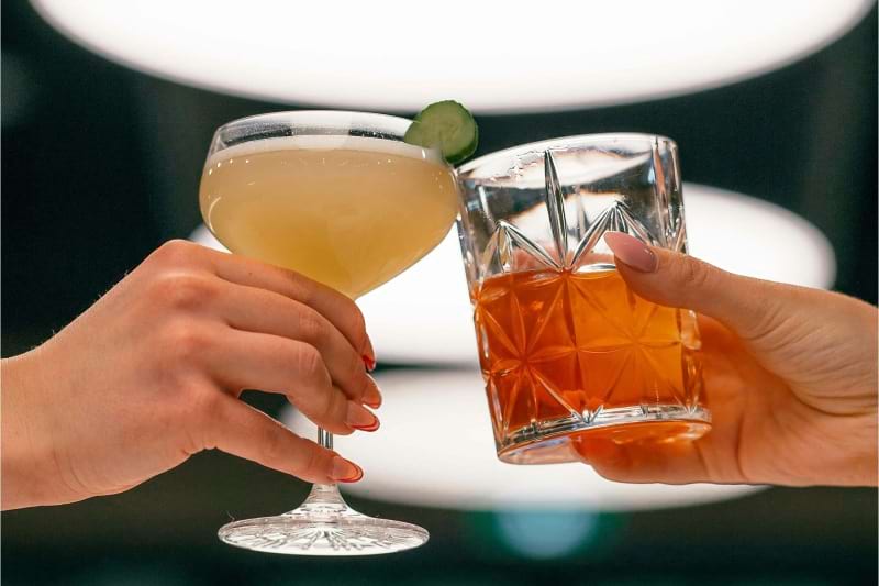 hands holding glasses with cocktails