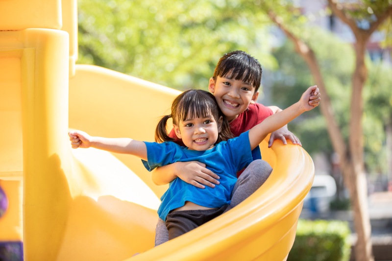 a couple of kids on a yellow slide